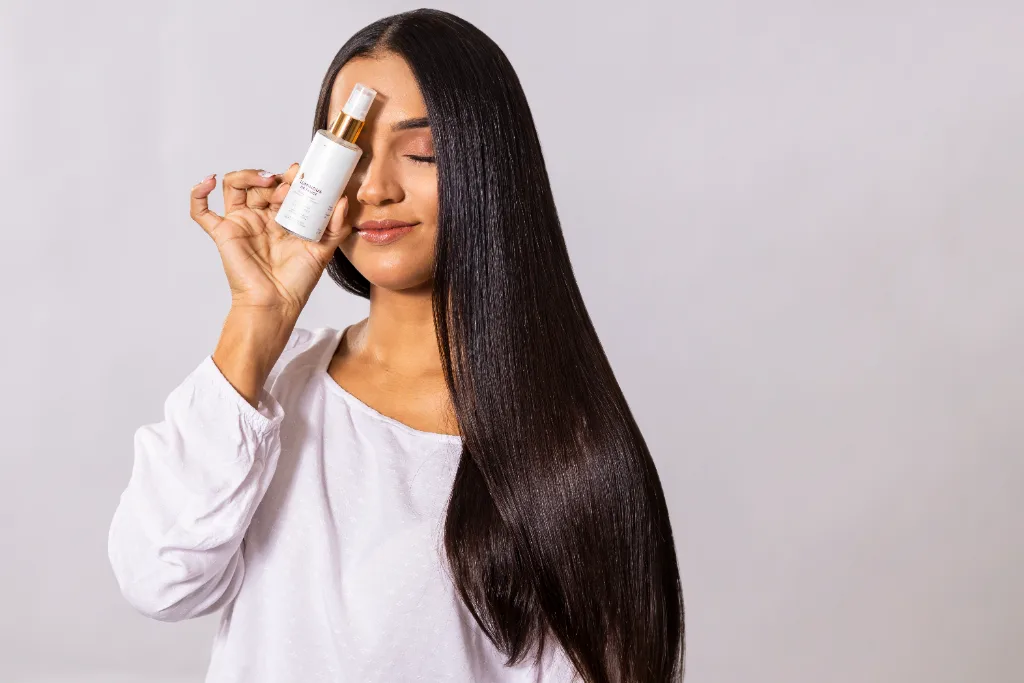 Modelo com cabelo longo escuro segurando produto de haircare Faube